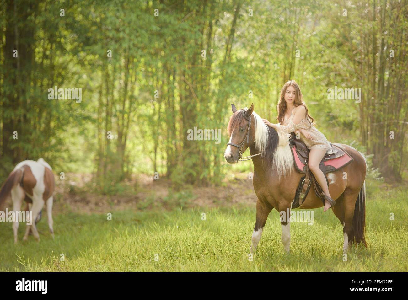 Femme pieds nus à cheval dans un pré, Thaïlande Banque D'Images