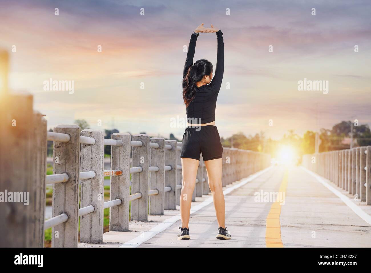 Vue arrière d'un coureur se tenant sur un pont au lever du soleil, en Thaïlande Banque D'Images