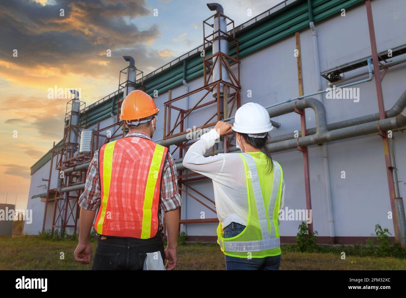 Deux ingénieurs qui étudient les plans de construction devant une usine, en Thaïlande Banque D'Images