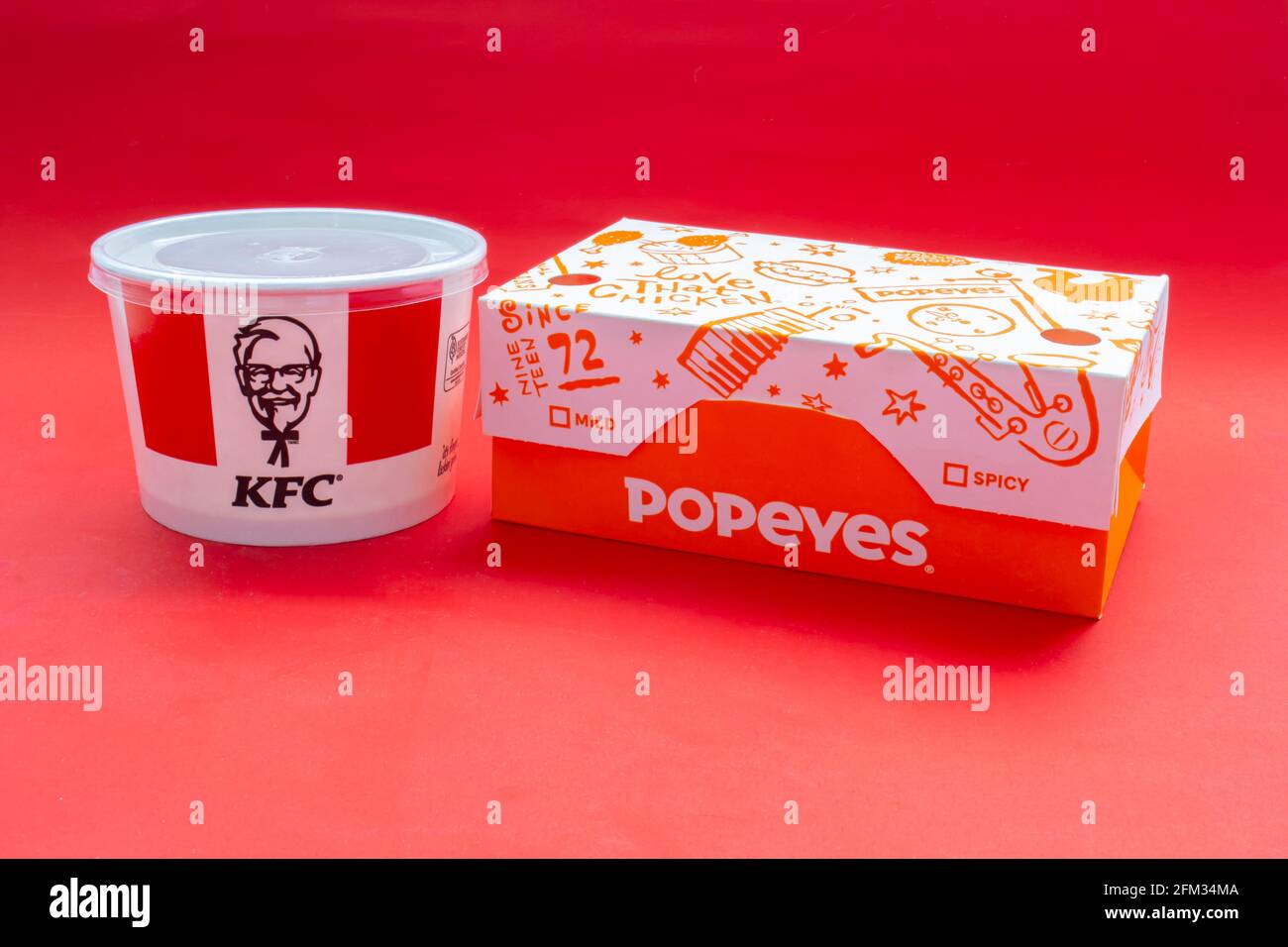 Calgary, Alberta, Canada. 5 mai 2021. Boîtes KFC et Popeyes Fast Food sur fond rouge. Banque D'Images