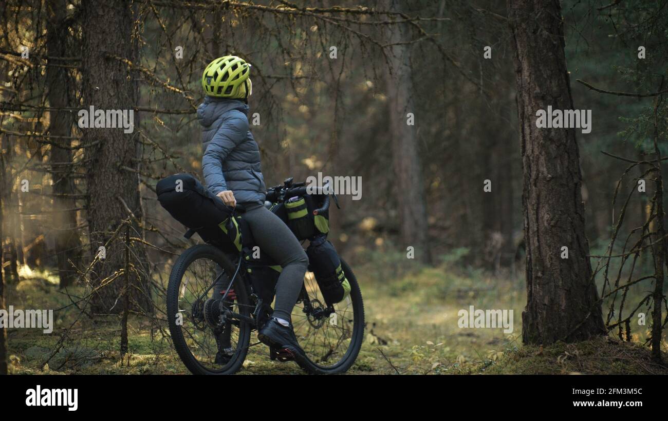 La femme voyage sur le terrain mixte vélo de tournée avec vélo bikepacking. Le voyage du voyageur avec des sacs de vélo. Parc de la forêt magique. Banque D'Images