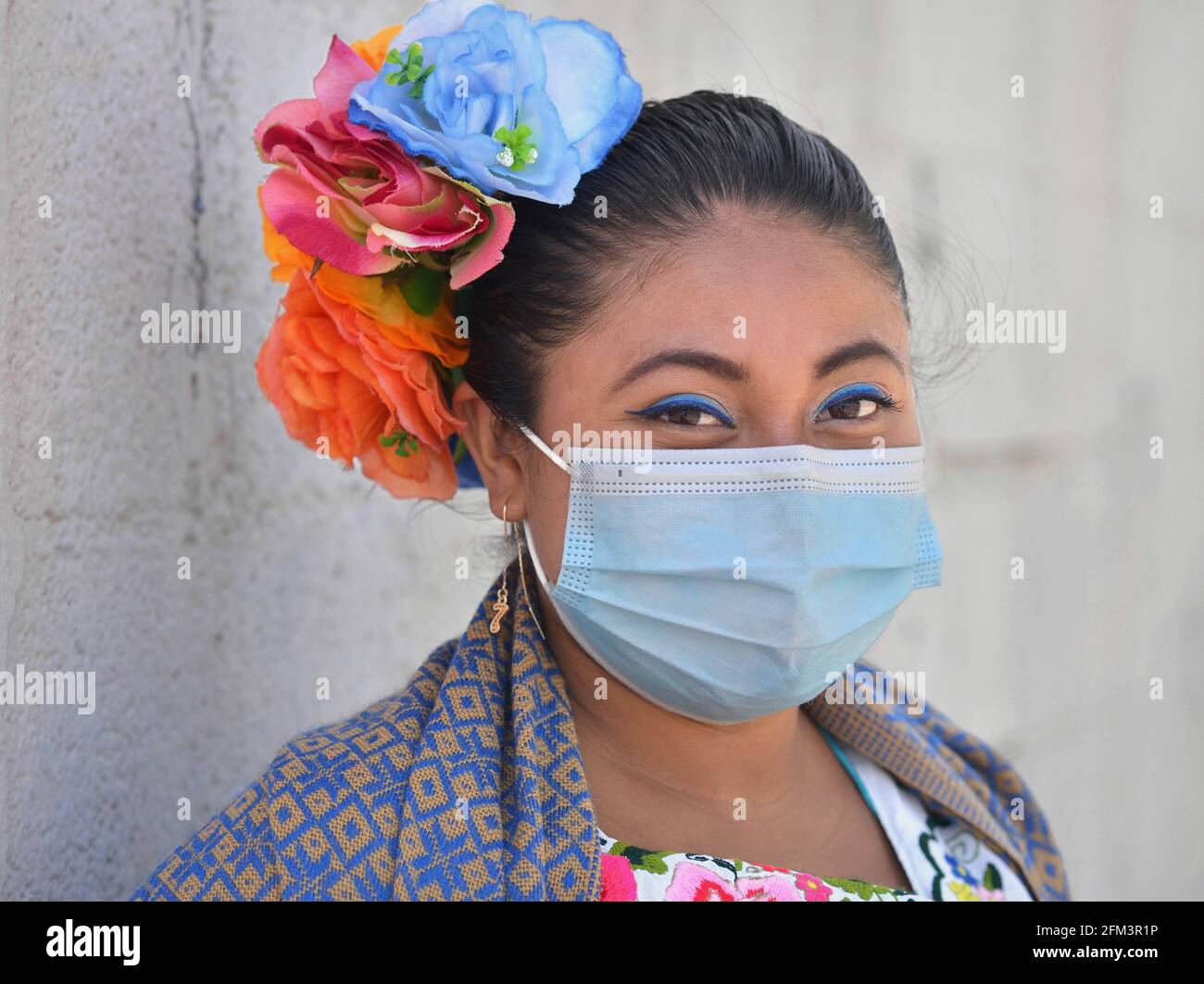 Une jeune Yucatecan mexicaine de chubby, dont les cheveux sont fleuris, porte un masque chirurgical bleu clair lors de la pandémie mondiale du coronavirus. Banque D'Images