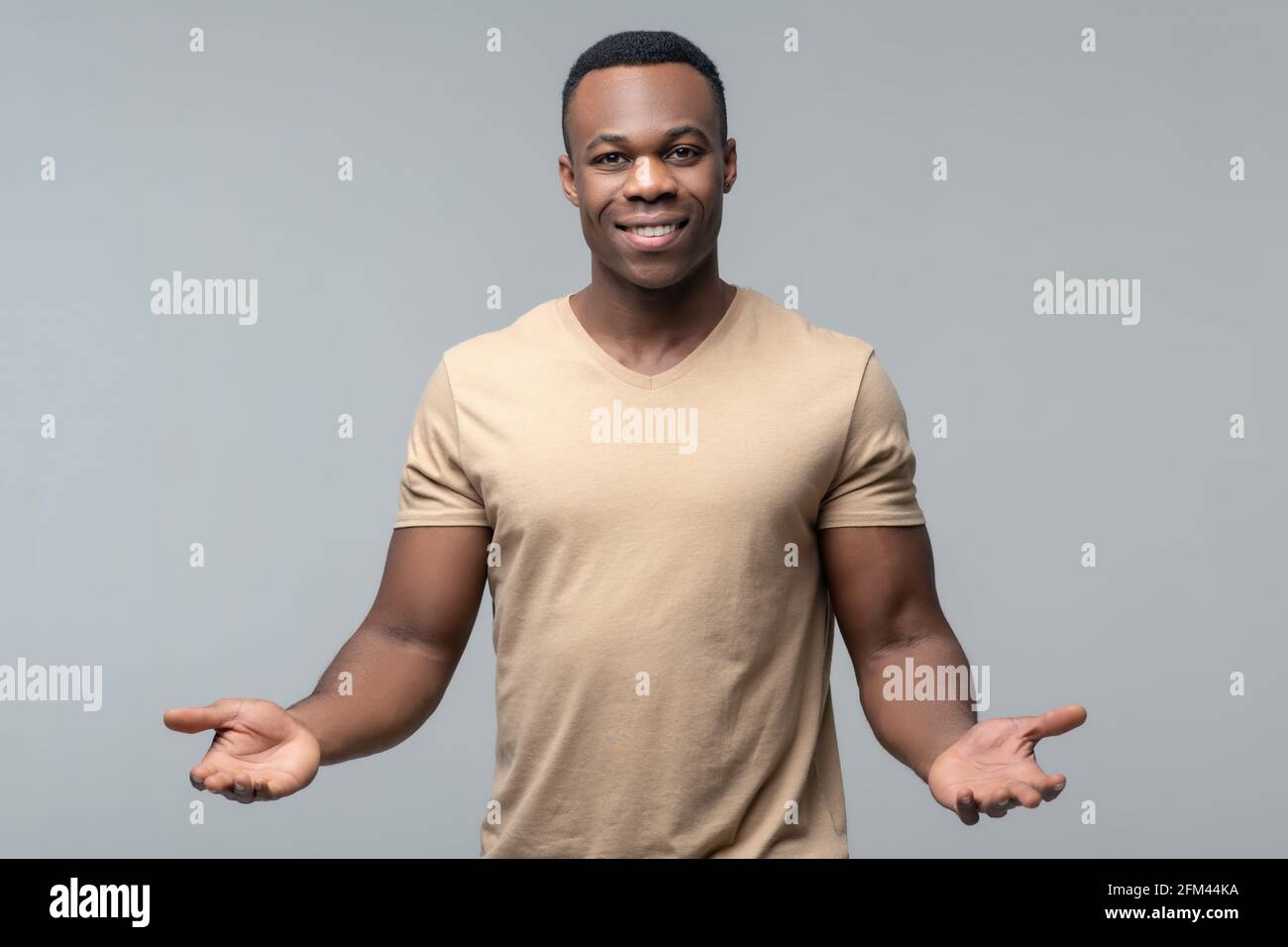 Sympathique homme à la peau sombre montrant des paumes ouvertes Banque D'Images