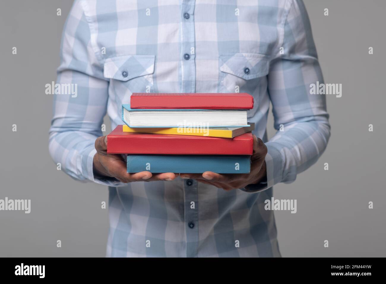 Les mains des mans à la peau sombre tiennent des manuels scolaires Banque D'Images