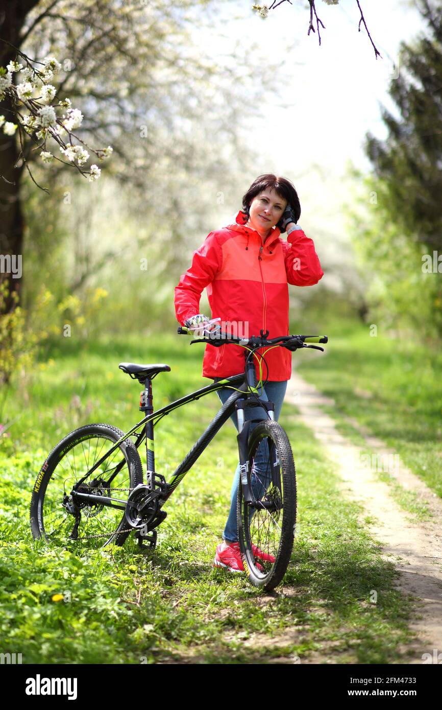 Belle femme sur un vélo dans un jardin de printemps fleuri. Banque D'Images