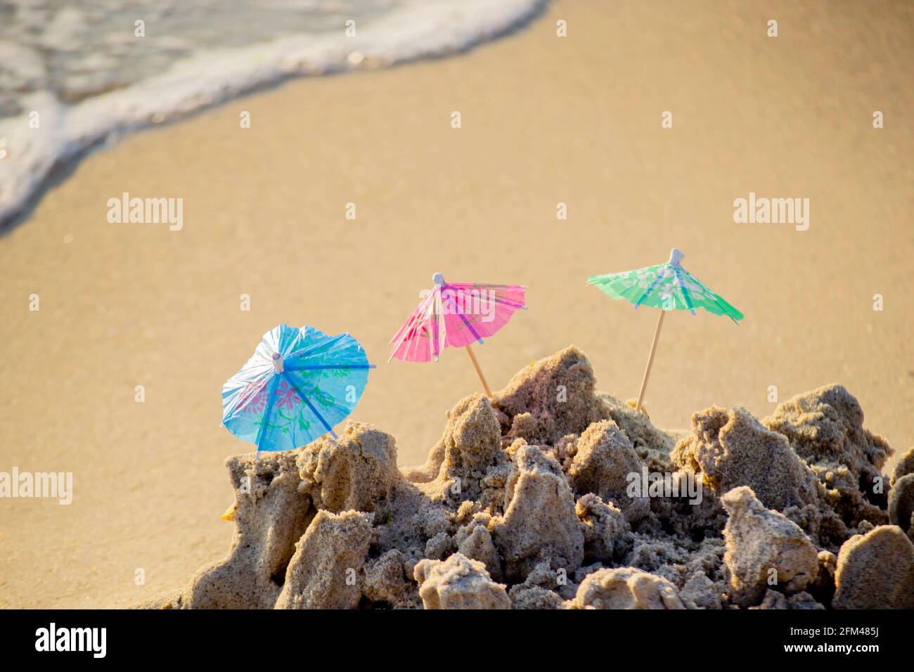 Trois petits parasols de plage en papier pour le stand à cocktails dans le sable Banque D'Images
