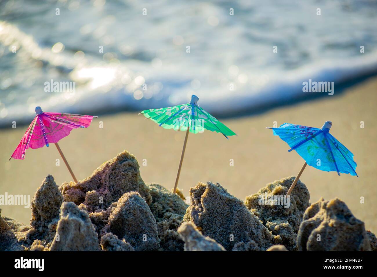 Trois petits parasols de plage en papier pour le stand à cocktails dans le sable Banque D'Images