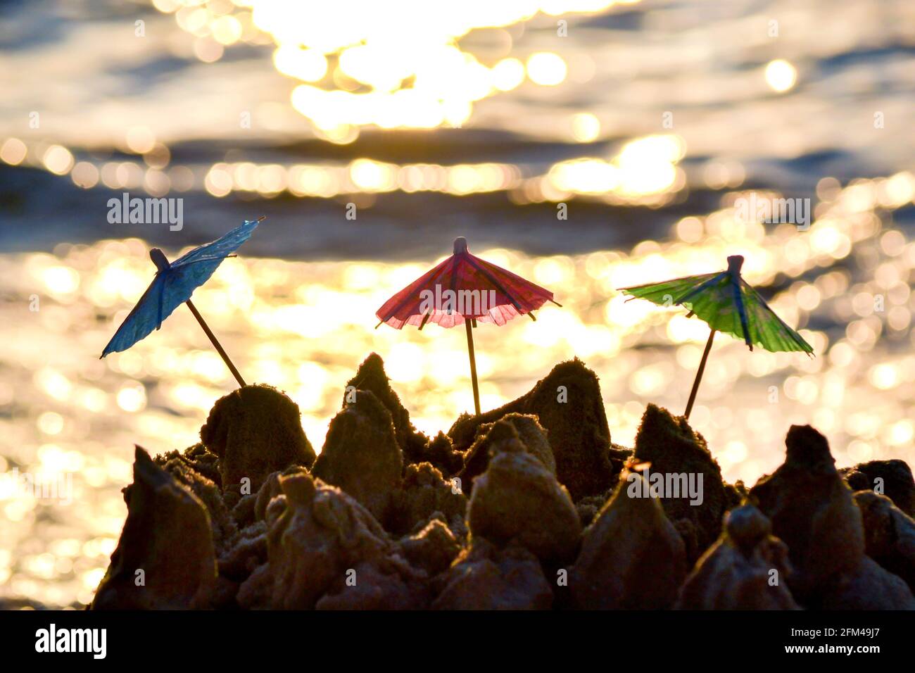 Trois petits parasols de plage en papier pour le stand à cocktails dans le sable Banque D'Images