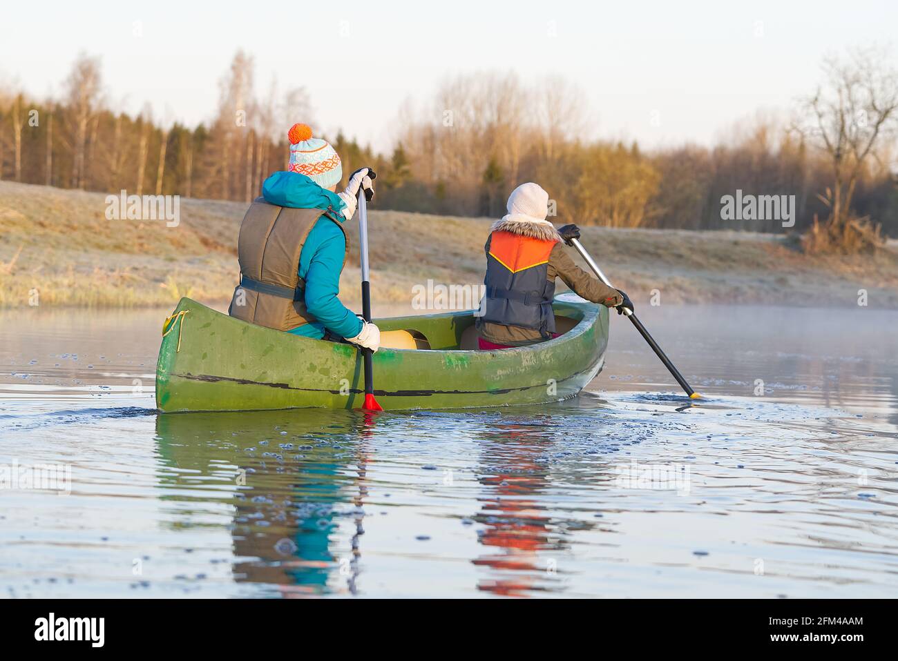 mère et fille ramer un canot au début du printemps tôt le matin. mode de  vie actif. Paysage du matin, brouillard au bord de la rivière du matin et  les gens sur