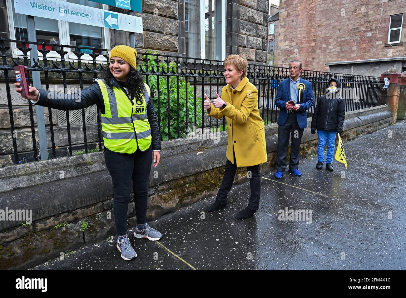 Le premier ministre et chef du SNP Nicola Sturgeon et le candidat Roza Salih posent pour un selfie avec des électeurs à l'extérieur du bureau de vote de l'école Annette Street à Govanhill, Glasgow, où les électeurs votent aux élections parlementaires écossaises. Date de la photo: Jeudi 6 mai 2021. Banque D'Images