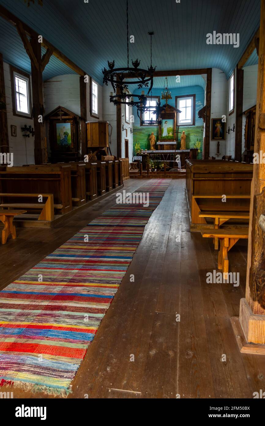 Intérieur d'une ancienne église en bois. Plafonds bleus, murs blancs, ragoûts en bois, sculptures folkloriques sur l'autel. Éclairage naturel au crépuscule pour une lumière douce. Banque D'Images