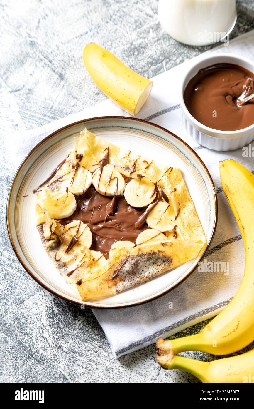 Crêpes, crêpes fines sur une assiette. Tartinade au chocolat et crêpes fourrées à la banane sur l'assiette. Crêpes savoureuses ou blini à la sauce sucrée. Banque D'Images