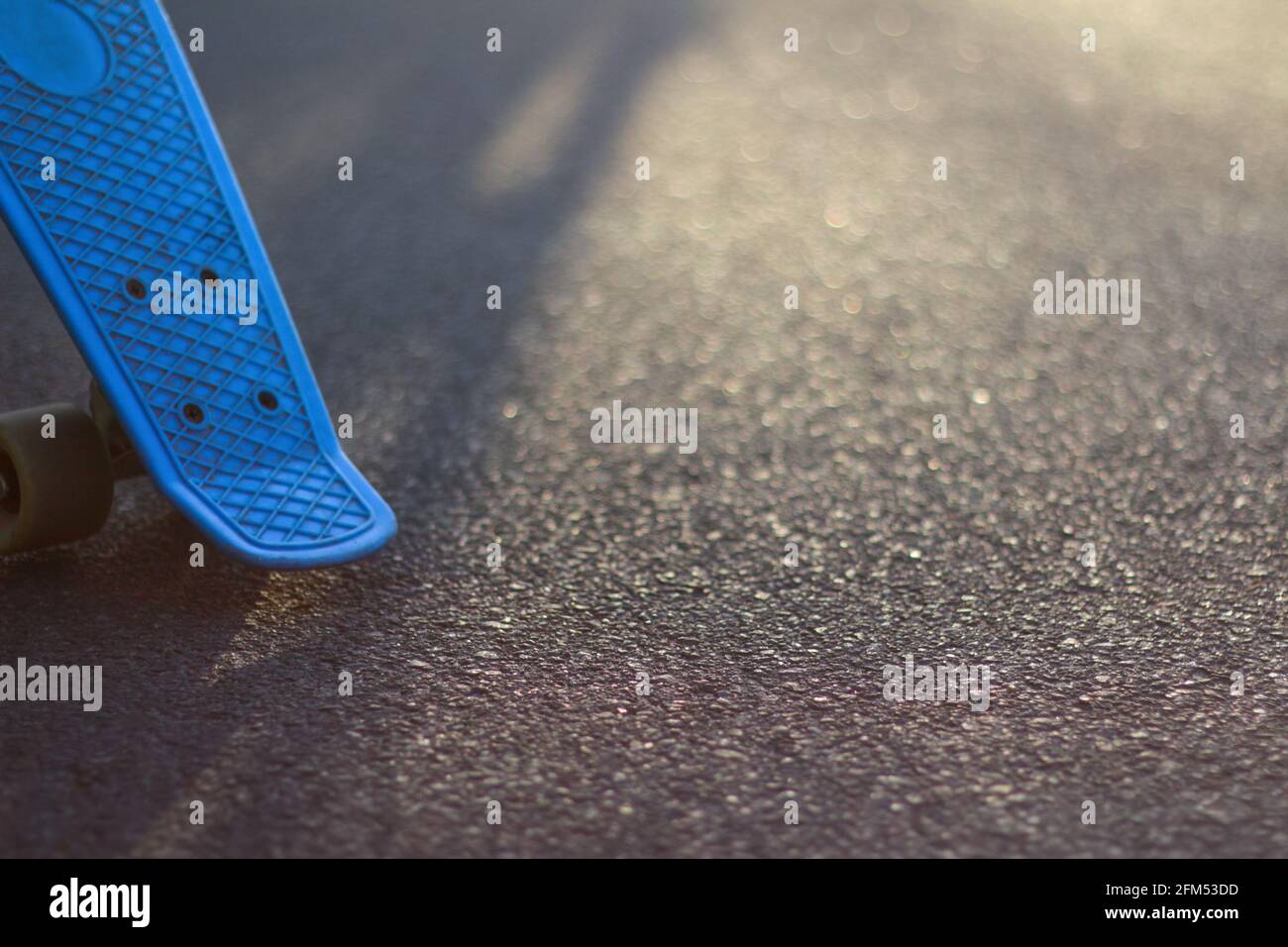 Flou artistique en gros plan sur le panneau bleu penny sur la route asphaltée en plein soleil. Bokeh flou. Mini-croiseur. Concept sport. Planche à roulettes debout à gauche Banque D'Images