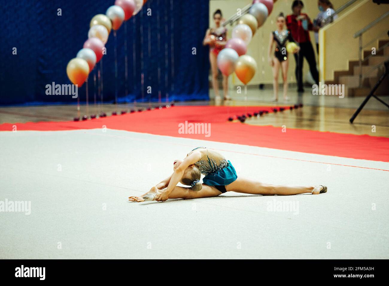 une fillette de gymnaste se produit avec un cerceau. un athlète flexible se produit sur une stand lors des compétitions Banque D'Images