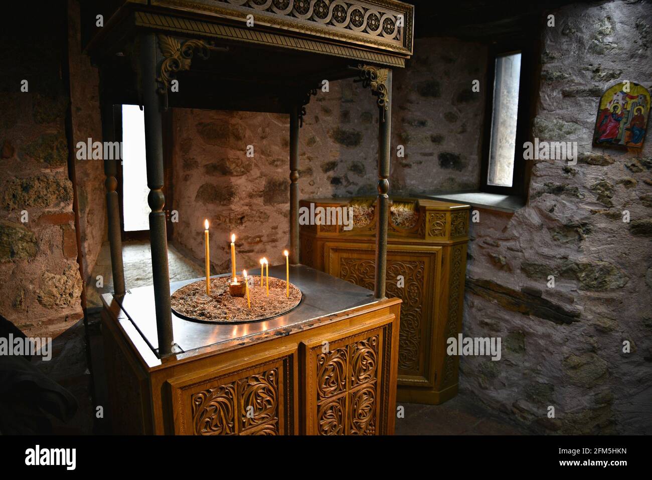 Église byzantine mur en pierre intérieur avec un stand de bougie au Grand Meteoron Saint Monastère à Kalambaka, Thessalie Grèce. Banque D'Images