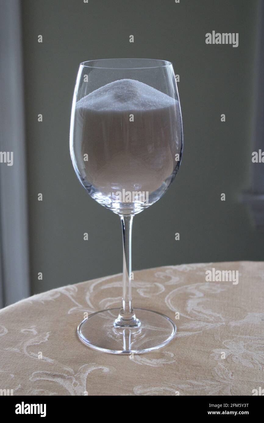 Sucre blanc raffiné dans UN verre à vin transparent Banque D'Images