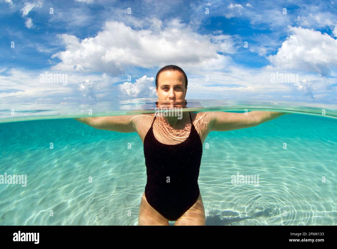 Moitié au-dessus et moitié au-dessous de la photo d'une femme dans les eaux des Caraïbes. Banque D'Images