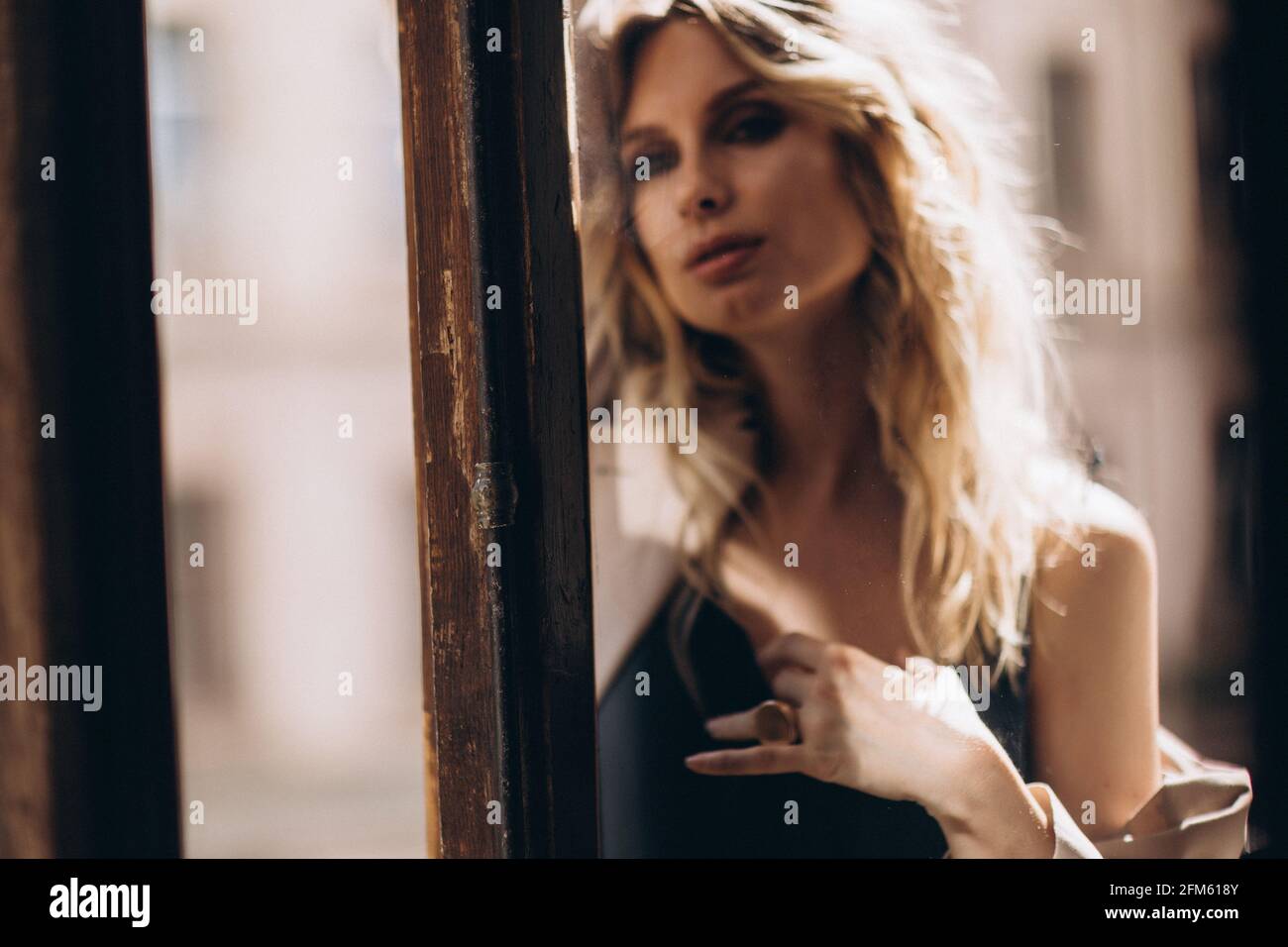 Portrait artistique défoqué d'une belle femme blonde aux yeux fumés avec maquillage à travers le verre en teinte beige. Hors foyer Banque D'Images