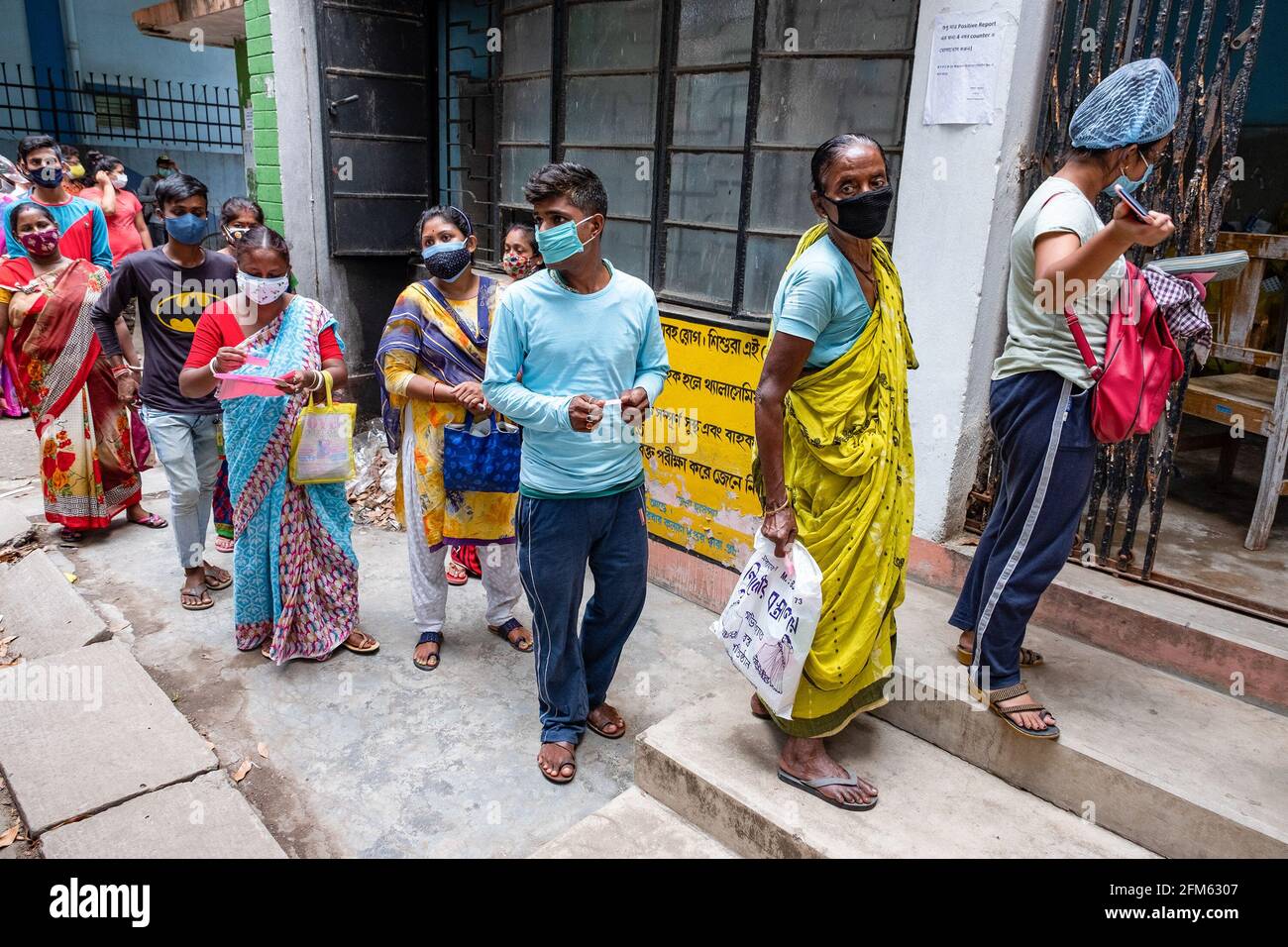 Les gens sont dans une longue file d'attente sans aucune distance sociale avant d'obtenir un test de Covid19 dans un kiosque de test à l'hôpital rural de Madhyamgram. Les tests Covid19 sont effectués partout en Inde pour dépister les patients infectés par la COVID19 afin de limiter le nombre croissant d'infections par la COVID19. Banque D'Images