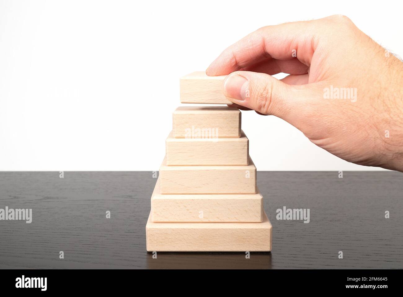 gros plan de la main de la personne empilant des blocs de bois formant un forme de pyramide Banque D'Images