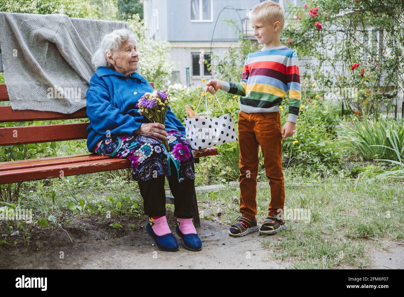 arrière-grand-mère de 90 ans, grand-mère avec petit-fils ensemble. Le petit-fils embrasse sa grand-mère bien-aimée. Le petit-fils est venu en grand-mère avec de la fleur Banque D'Images