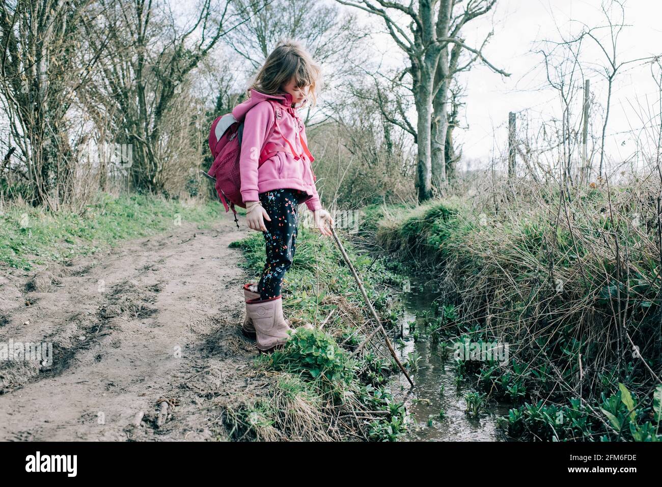 une petite fille à pied et à explorer la nature avec son bâton dedans un flux Banque D'Images