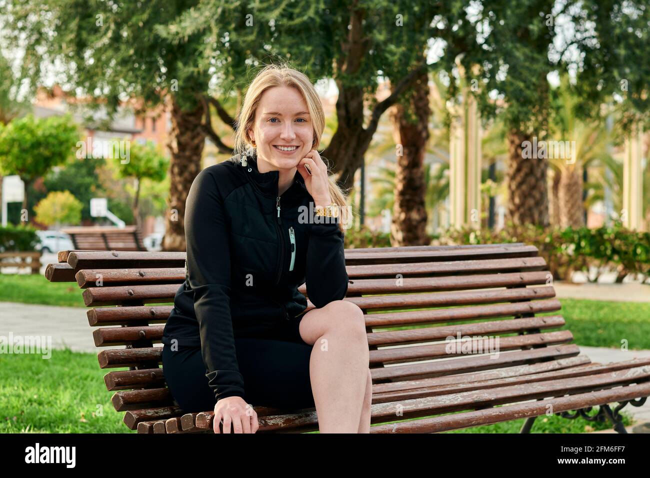 Portrait d'une jeune femme blonde souriant à l'appareil photo dans un parc Banque D'Images