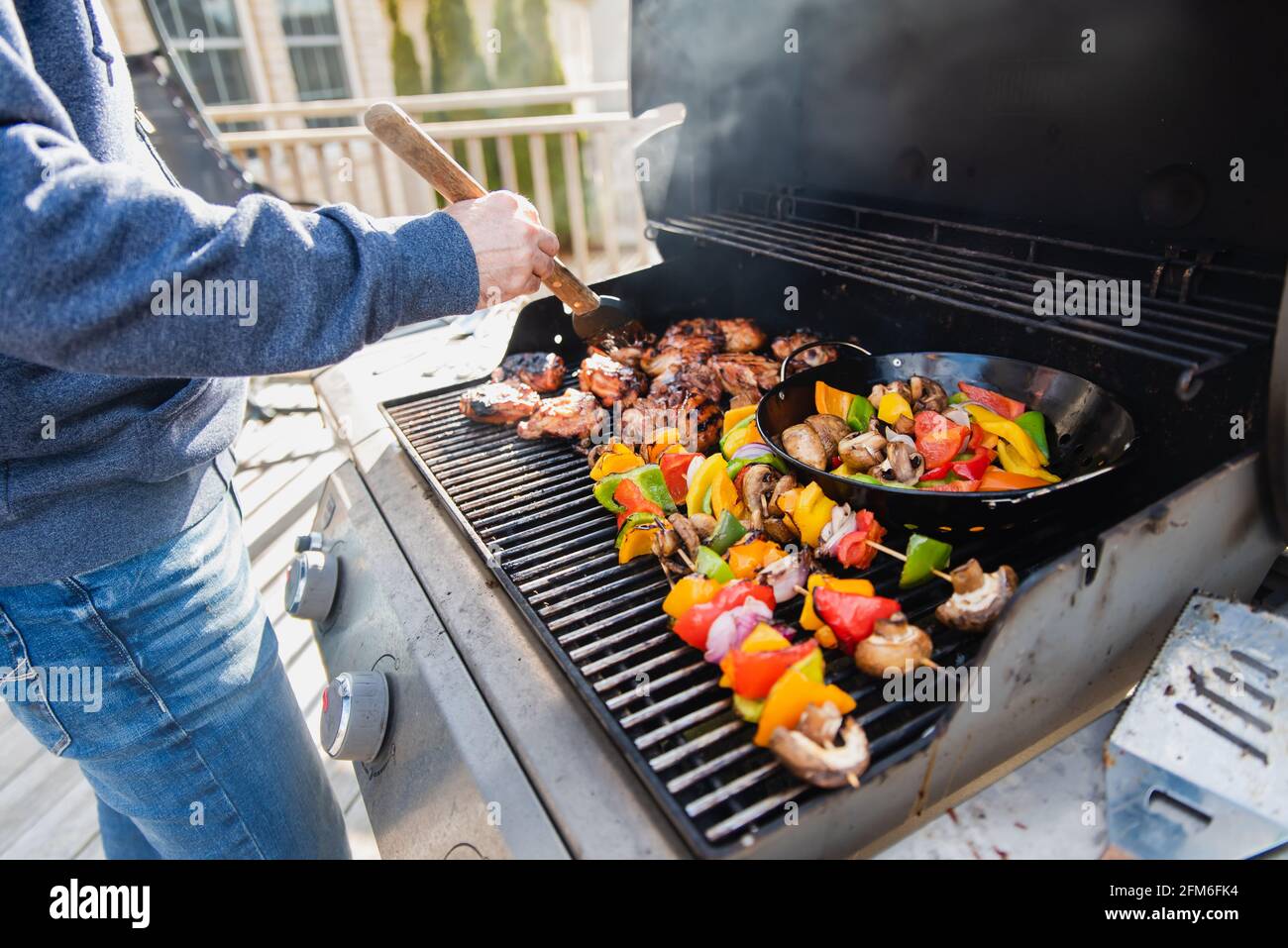 Homme qui fait griller du poulet et des légumes à l'extérieur sur un  barbecue à gaz Photo Stock - Alamy
