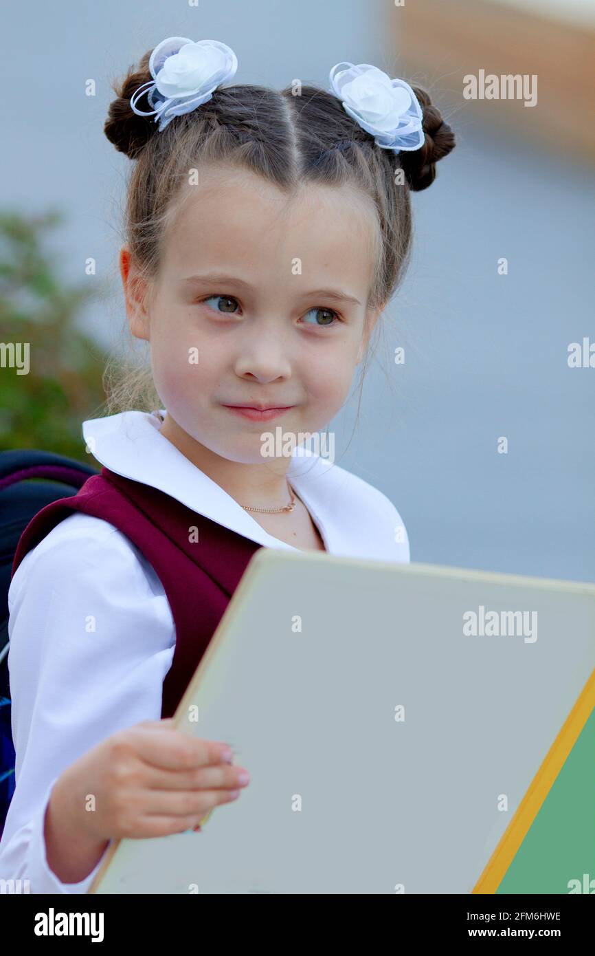 Adorable petite écolière lisant un livre à l'extérieur sur la cour de l'école. Concept éducatif. Copier l'espace Banque D'Images