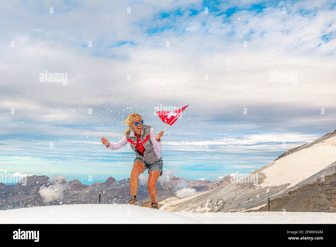 Femme trekking dans la tempête de neige avec un drapeau suisse. Sommet du glacier de Titlis dans les Alpes Uri à 3028 mètres. Cantons d'Obwalden et de Berne, Suisse Banque D'Images