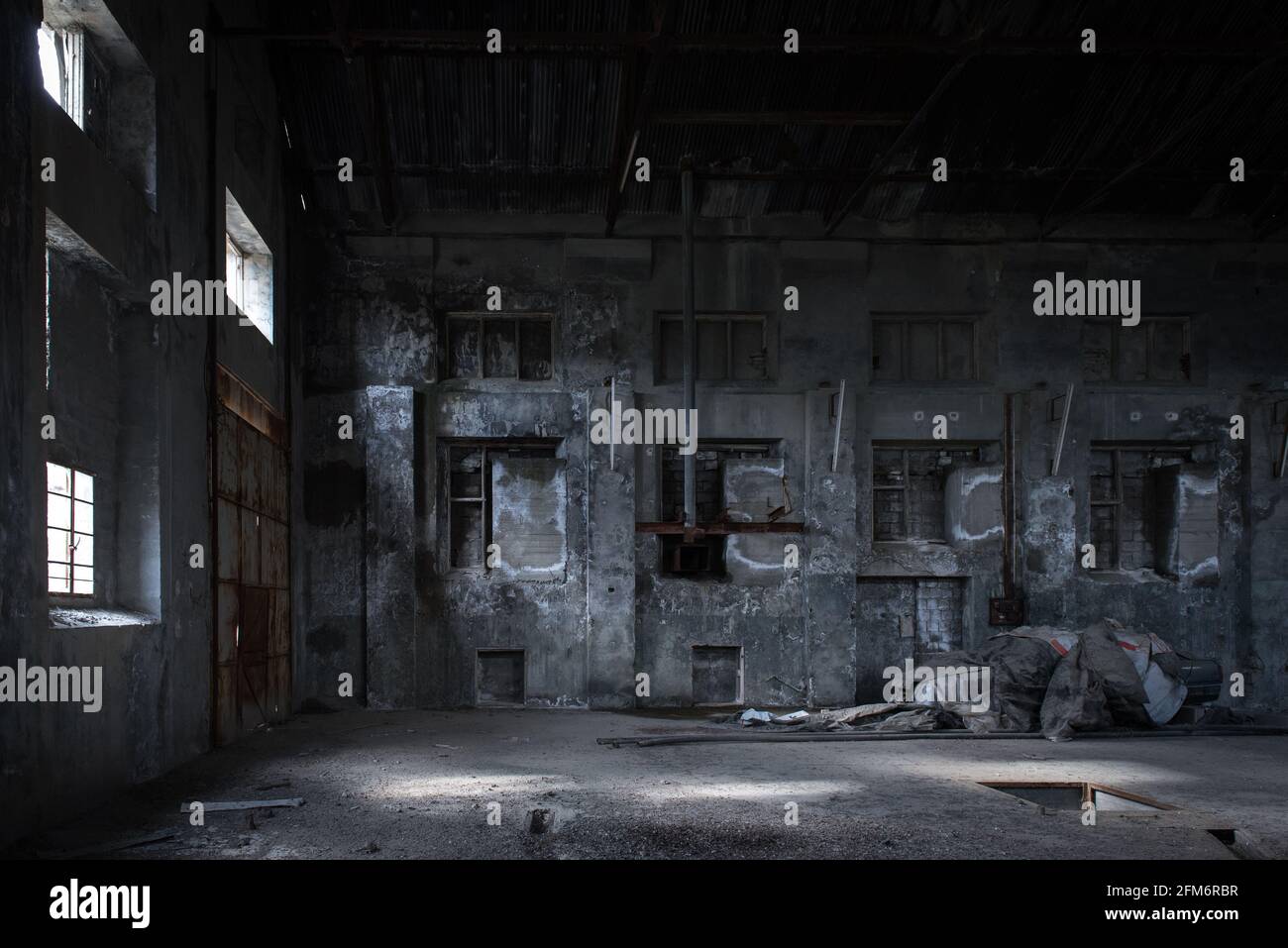 Toile de fond du bâtiment industriel. Intérieur de l'usine abandonnée avec des murs en béton vitraux, des fenêtres vitresses et des pièces d'équipement ancien Banque D'Images