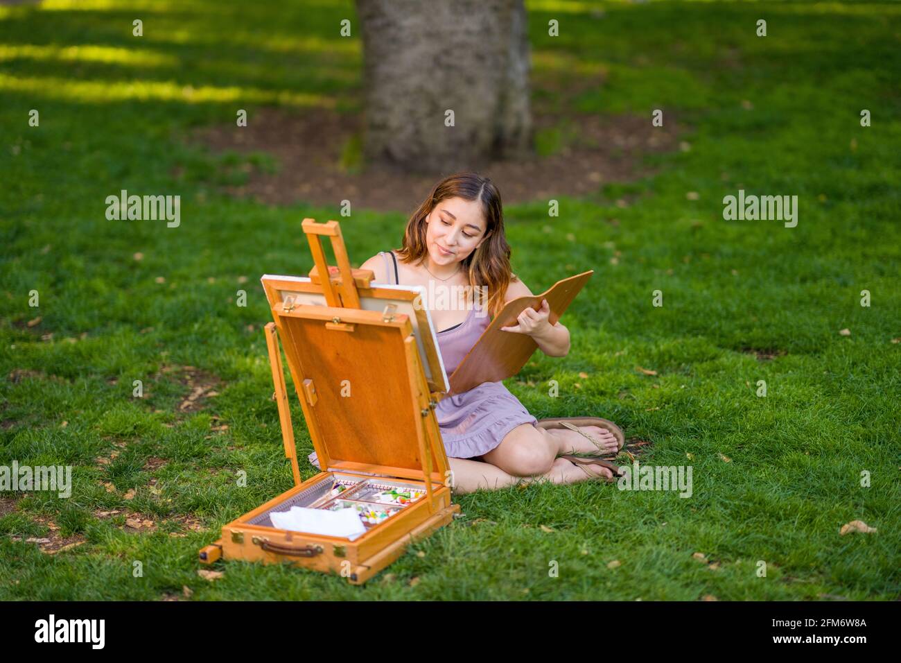 Petite Jeune Femme asiatique étudiant peinture dans le parc utilisation Une armoire Easel Banque D'Images