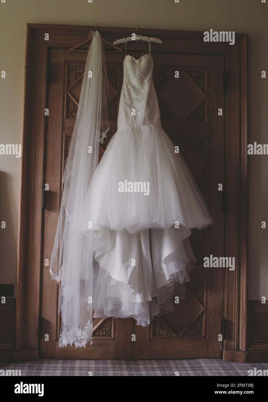 Robe de mariage et voile suspendu de porte en bois dans vintage chambre Banque D'Images