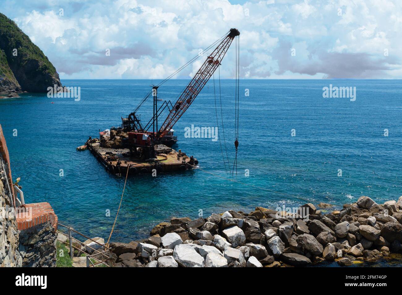 Riomaggiore, Ligurie, Italie. Juin 2020. À l'extérieur de la marina, une plate-forme flottante avec une drague fait l'entretien de la barrière rocheuse artificielle. Banque D'Images