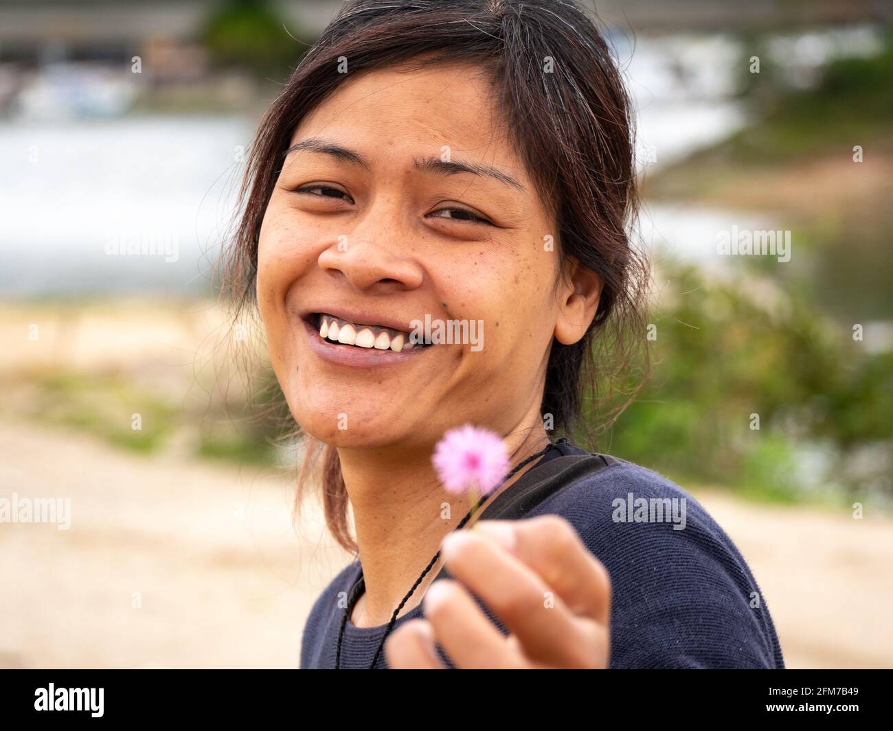 Guatape, Antioquia, Colombie - avril 4 2021 : jeune femme asiatique tenant une petite fleur et regardant la caméra Banque D'Images