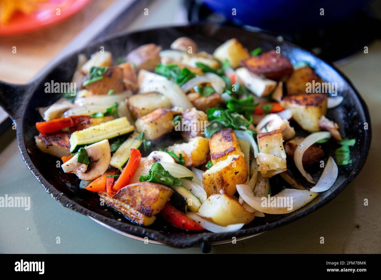 Pommes de terre et légumes. Pommes de terre roussettes frites avec oignons, poivron rouge, épinards, champignons et courgettes. Banque D'Images