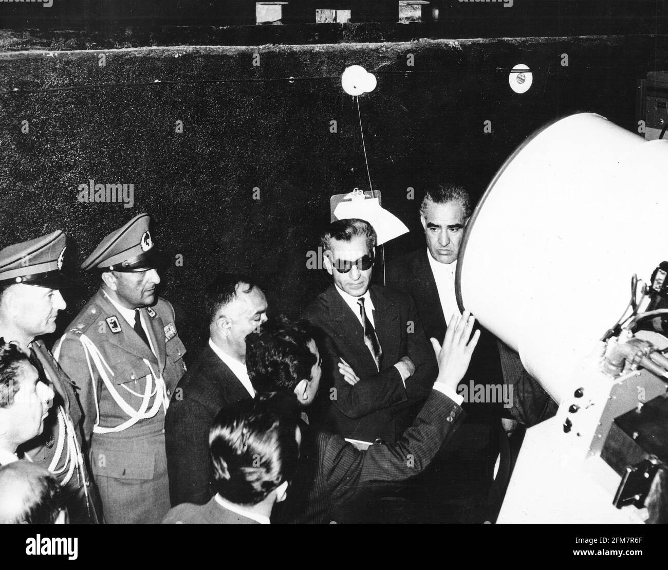 Le fonctionnement de la caméra Baker-Nunn à la station de Shiraz, en Iran, est expliqué à Mohammad Reza Pahlavi, le Shah d'Iran, et à son parti le 26 avril 1959. Les appareils photo Baker-Nunn sont exploités par l'observatoire astrophysique Smithsonian dans le cadre d'une subvention de la NASA pour suivre et photographier optiquement des engins spatiaux.Credit: NASA via CNP | usage dans le monde entier Banque D'Images