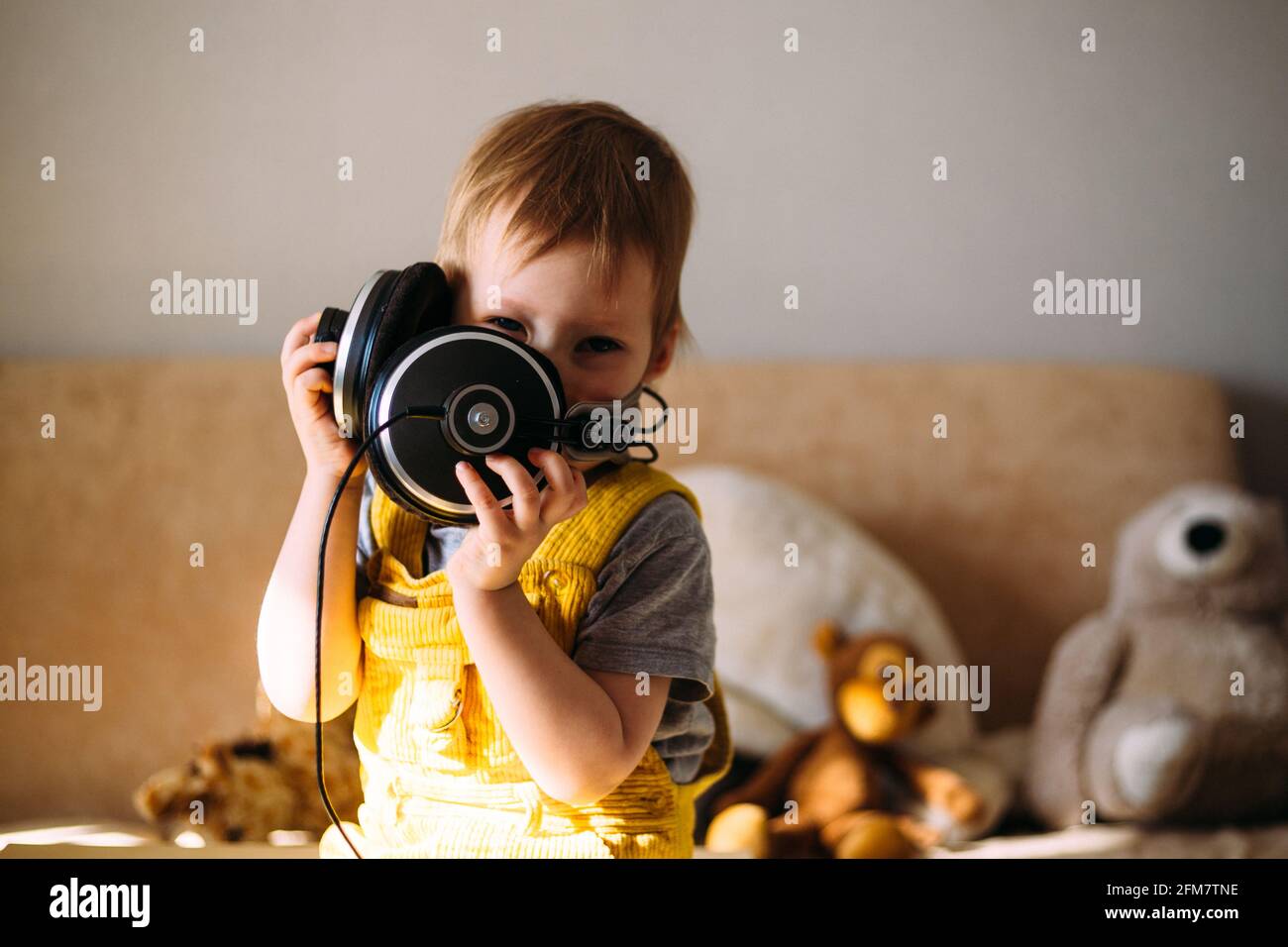 Drôle petit enfant s'amuser avec des écouteurs à la maison, portrait. Banque D'Images