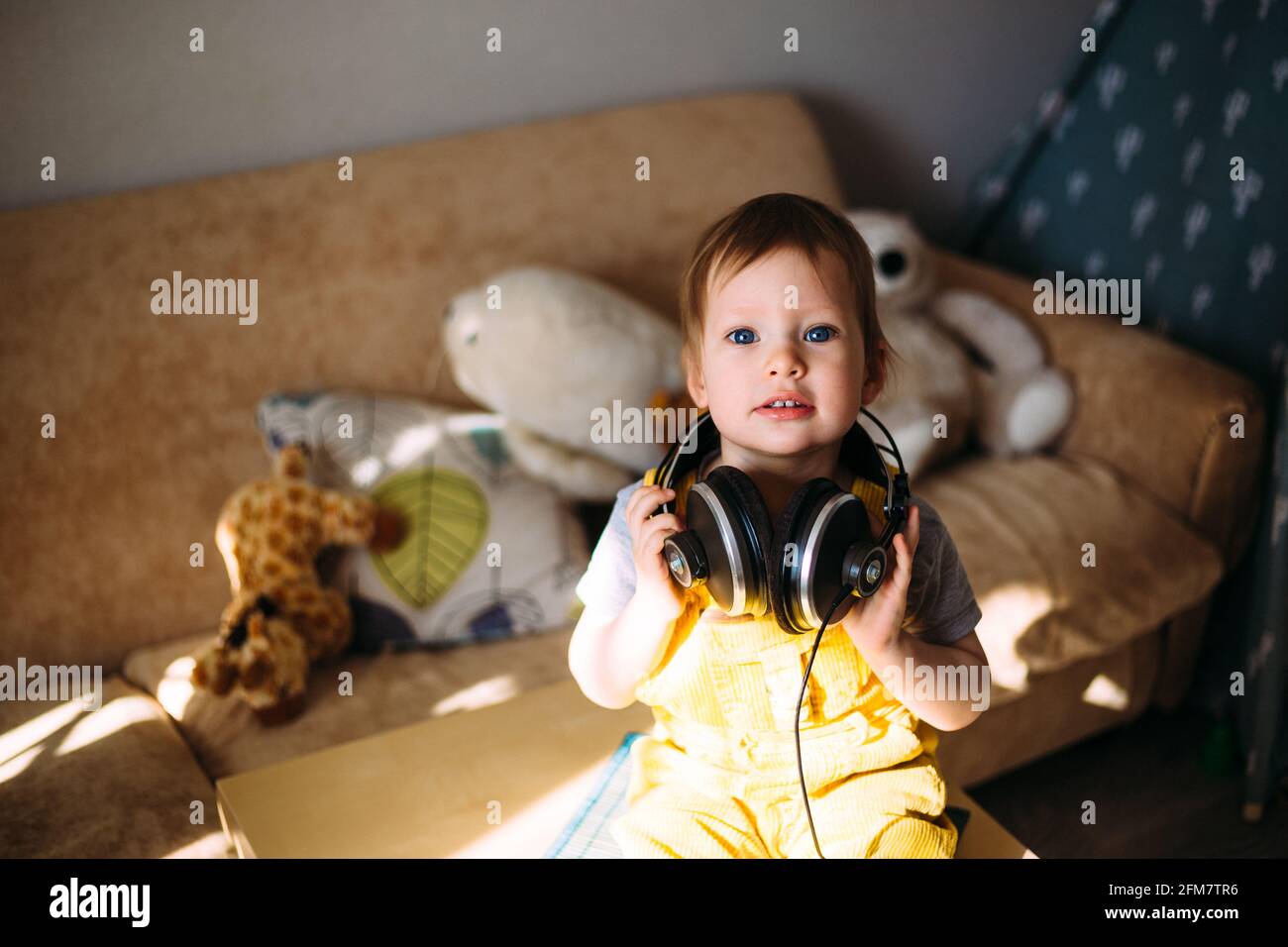 Drôle petit enfant s'amuser avec des écouteurs à la maison, portrait. Banque D'Images