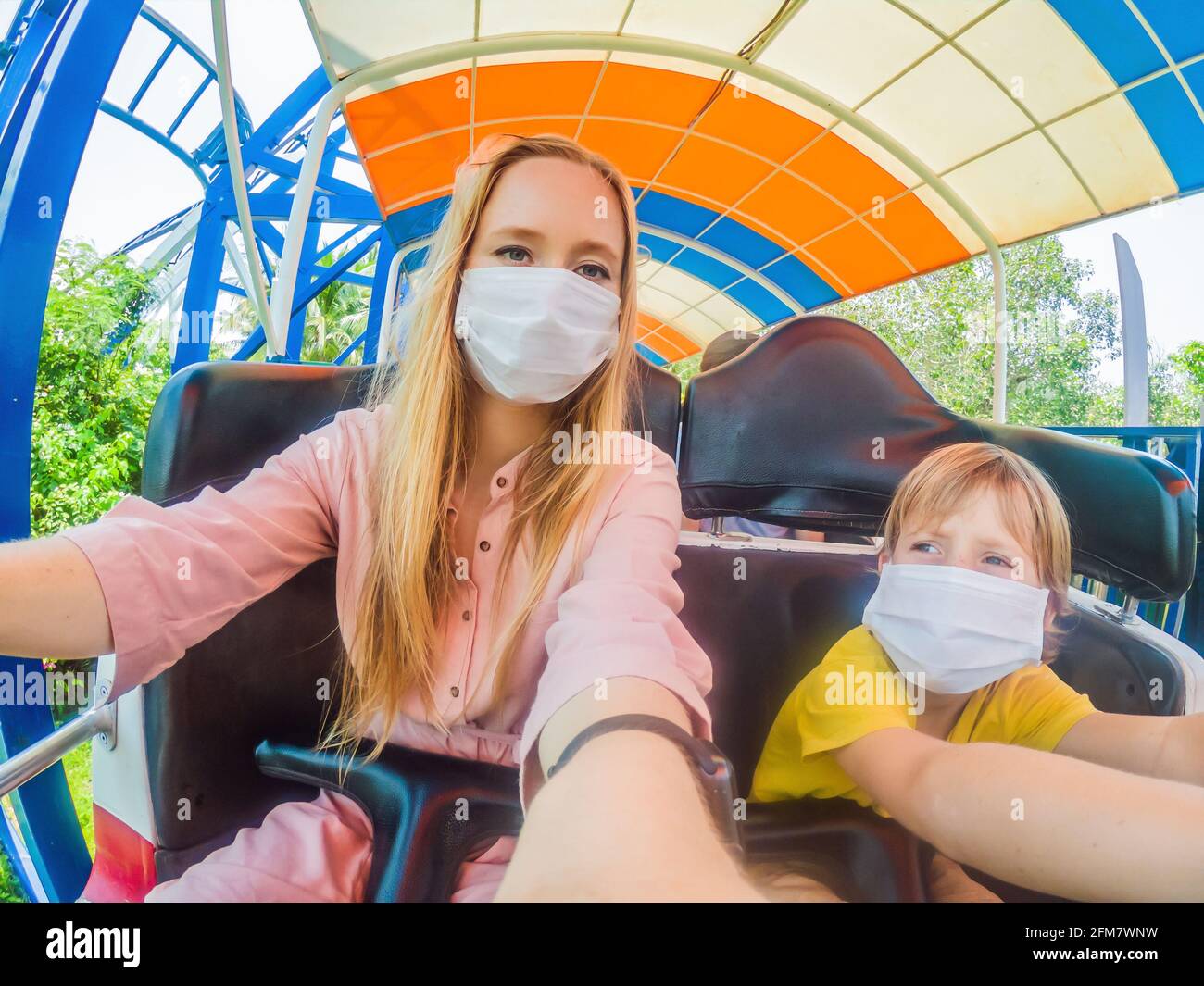 Famille portant un masque médical pendant le coronavirus COVID-19 à an parc d'attractions Banque D'Images