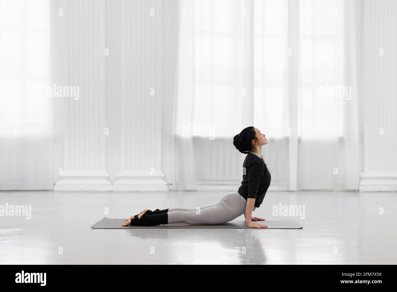 Posture Cobra. Belle jeune femme asiatique pratiquant le yoga pose sur tapis gris au studio de yoga. Banque D'Images