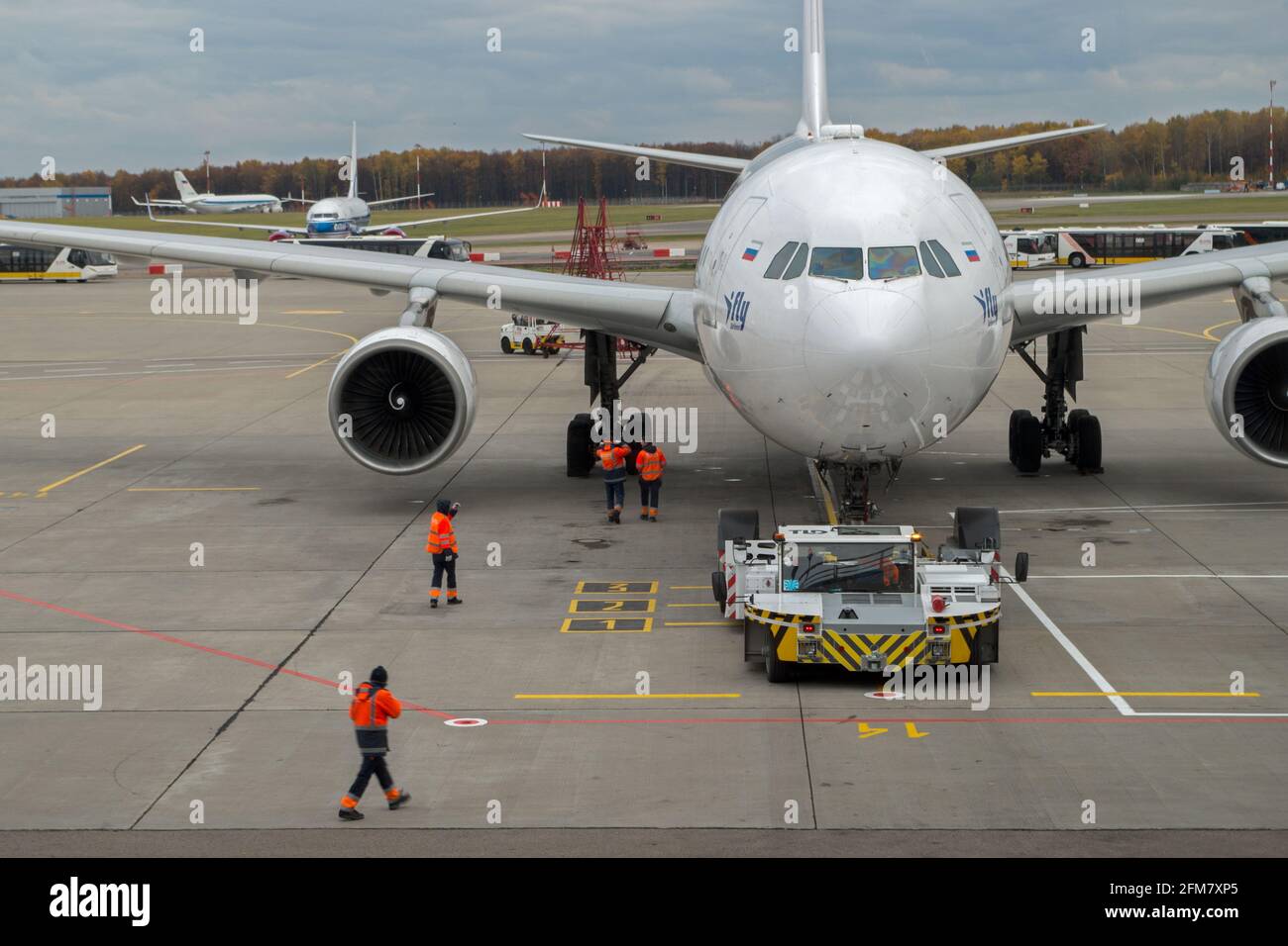 Préparation du personnel de l'aéroport en combinaison rouge de l'avion pour le transport sur la piste par transport spécial se trouvant sur l'emplacement de marquage. Banque D'Images