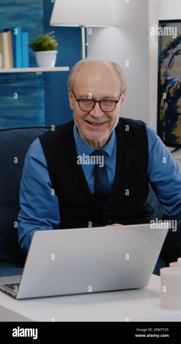 Un couple enthousiaste de retraités assis à la maison sur un canapé à l'aide d'un ordinateur portable parlant en vidéo avec des amis de la famille qui agite à la caméra pendant une réunion en ligne. Concept de style de vie de connexion en quarantaine Banque D'Images