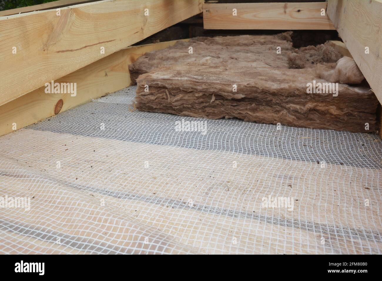 Isolation de toiture: Un gros plan de la laine minérale de toit, isolation de laine de verre sur une barrière à vapeur, membrane entre les solives de plafond en bois. Banque D'Images