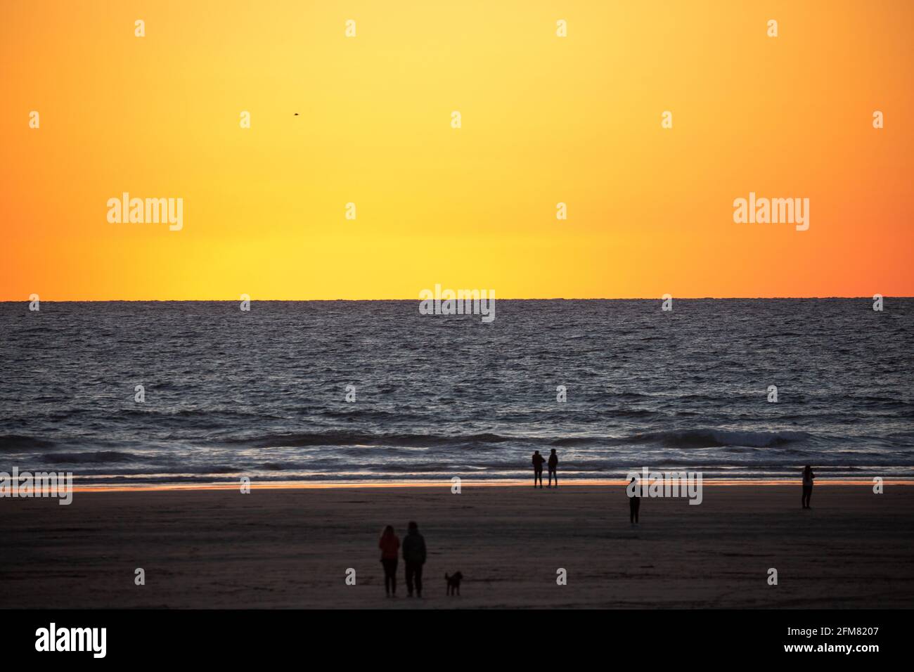 Les gens se tiennent sur la plage pour admirer le coucher de soleil sur la plage de Perranporth à Cornwall, au Royaume-Uni Banque D'Images