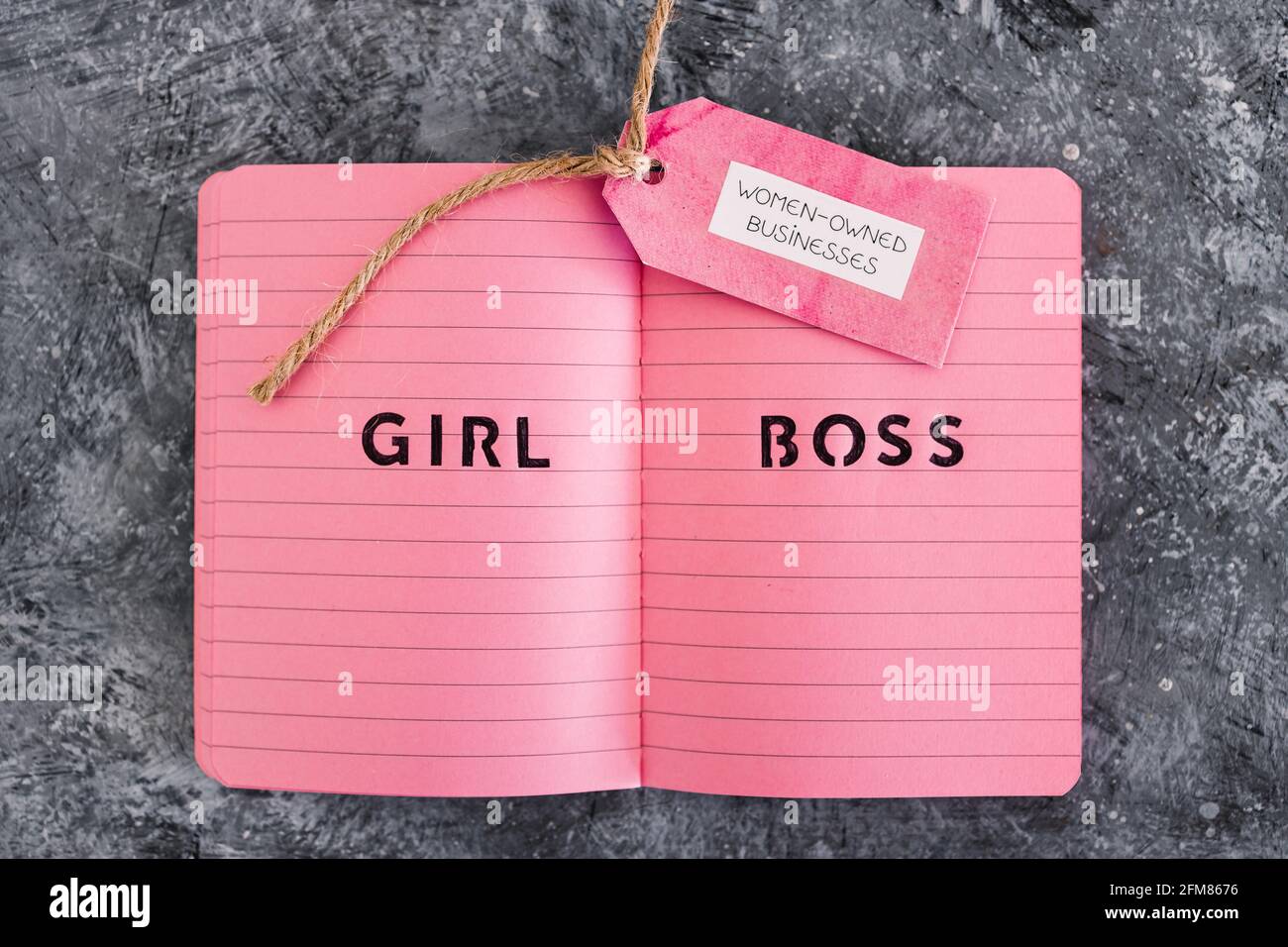 étiquette d'affaires appartenant à des femmes avec le texte de patron de fille sur le bloc-notes rose, soutenant l'égalité et l'égalité des chances Banque D'Images