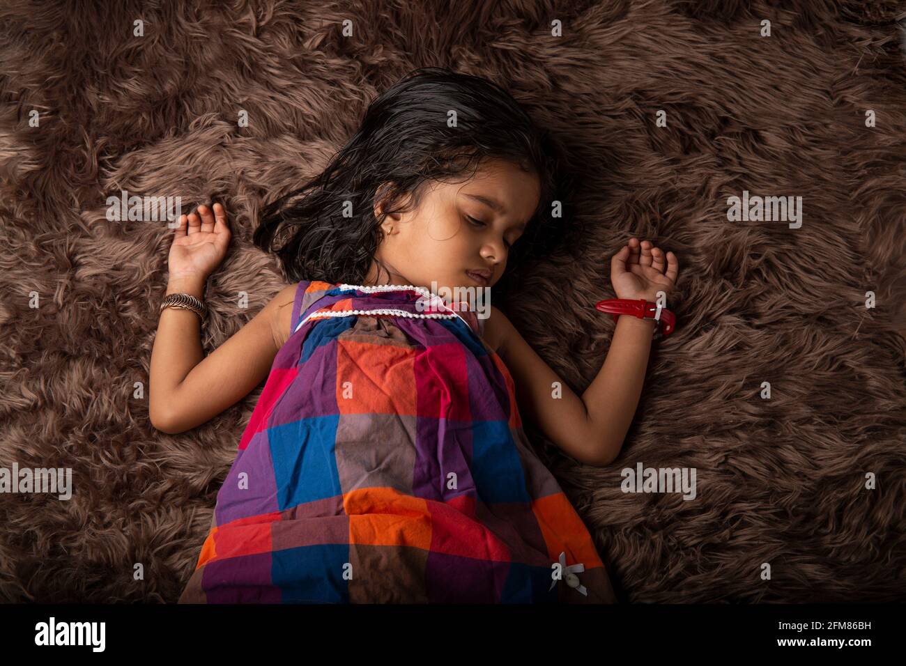 Sleeping Kid, une fille montrant différents gestares qui est couché sur un tapis synthatic qui est très doux et brun dans la couleur Banque D'Images