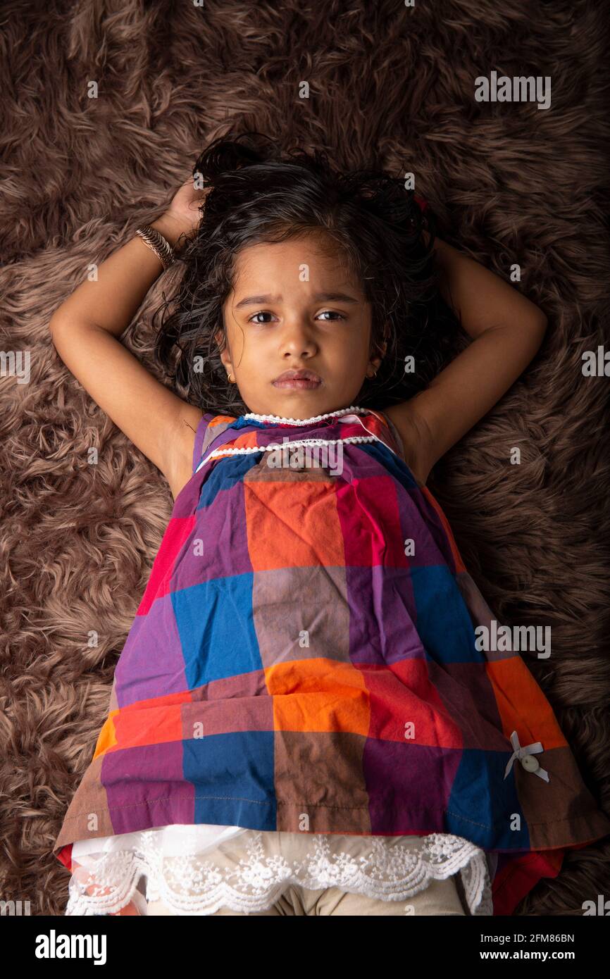 Sleeping Kid, une fille montrant différents gestares qui est couché sur un tapis synthatic qui est très doux et brun dans la couleur Banque D'Images