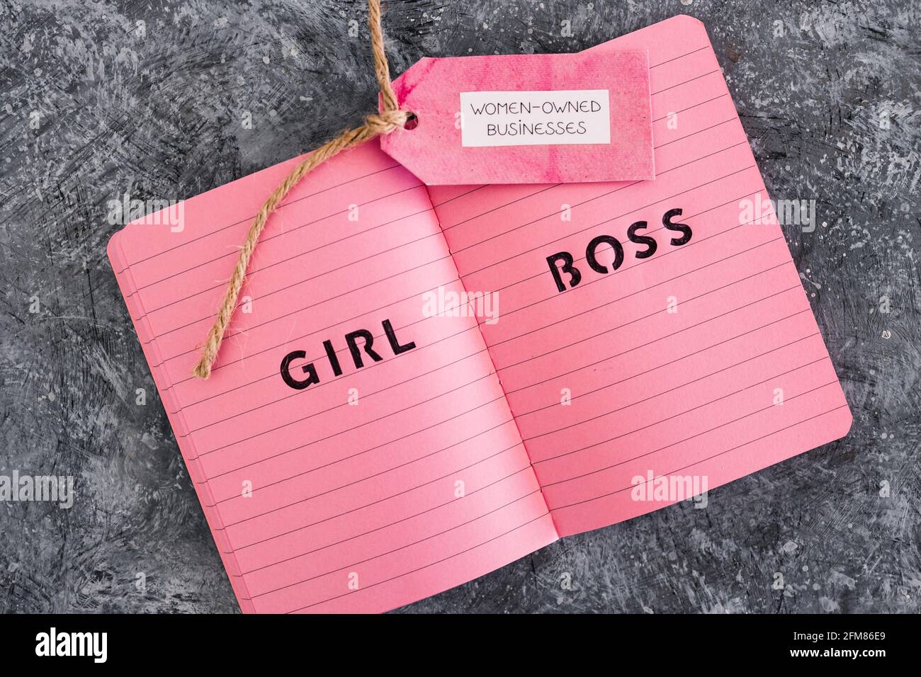 étiquette d'affaires appartenant à des femmes avec le texte de patron de fille sur le bloc-notes rose, soutenant l'égalité et l'égalité des chances Banque D'Images