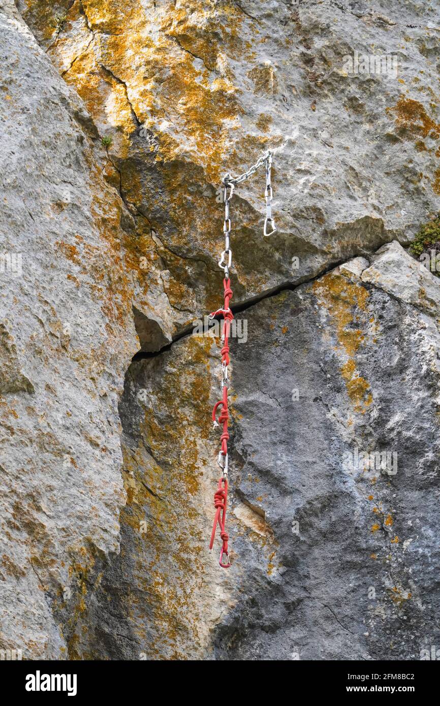 Corde d'escalade et ancres, laissées derrière le mur de roche naturelle. Banque D'Images